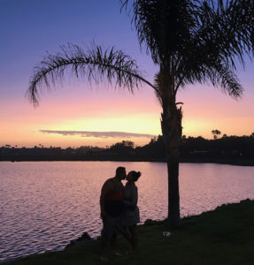 couple kissing along waterfront at sunset